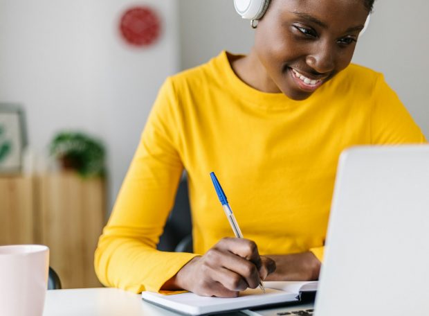 Smiling african woman student using laptop computer for online learning at home